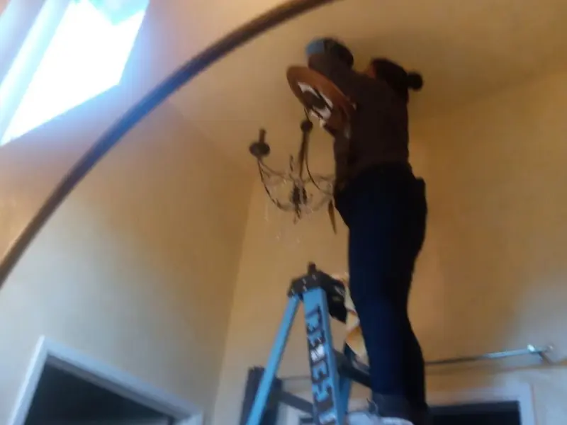 Electrician installing a chandelier in a St. Francis residence